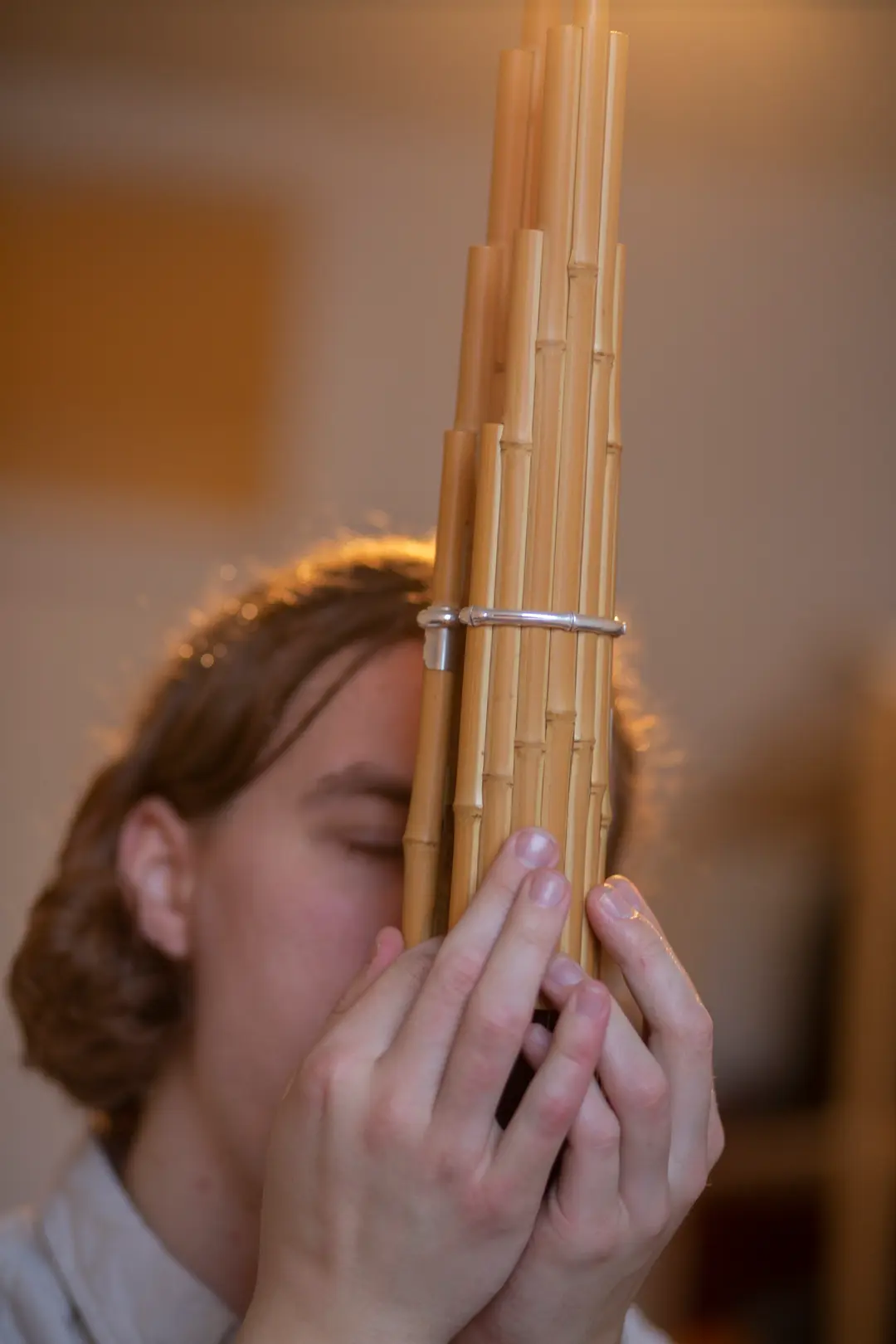 A person is playing a pan flute made of bamboo pipes.